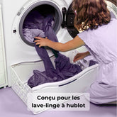 Cuvette à linge magnétique pliable: personne range des vêtements violets dans une machine à laver, panier fixé contre le lave-linge, conçu en Europe. 